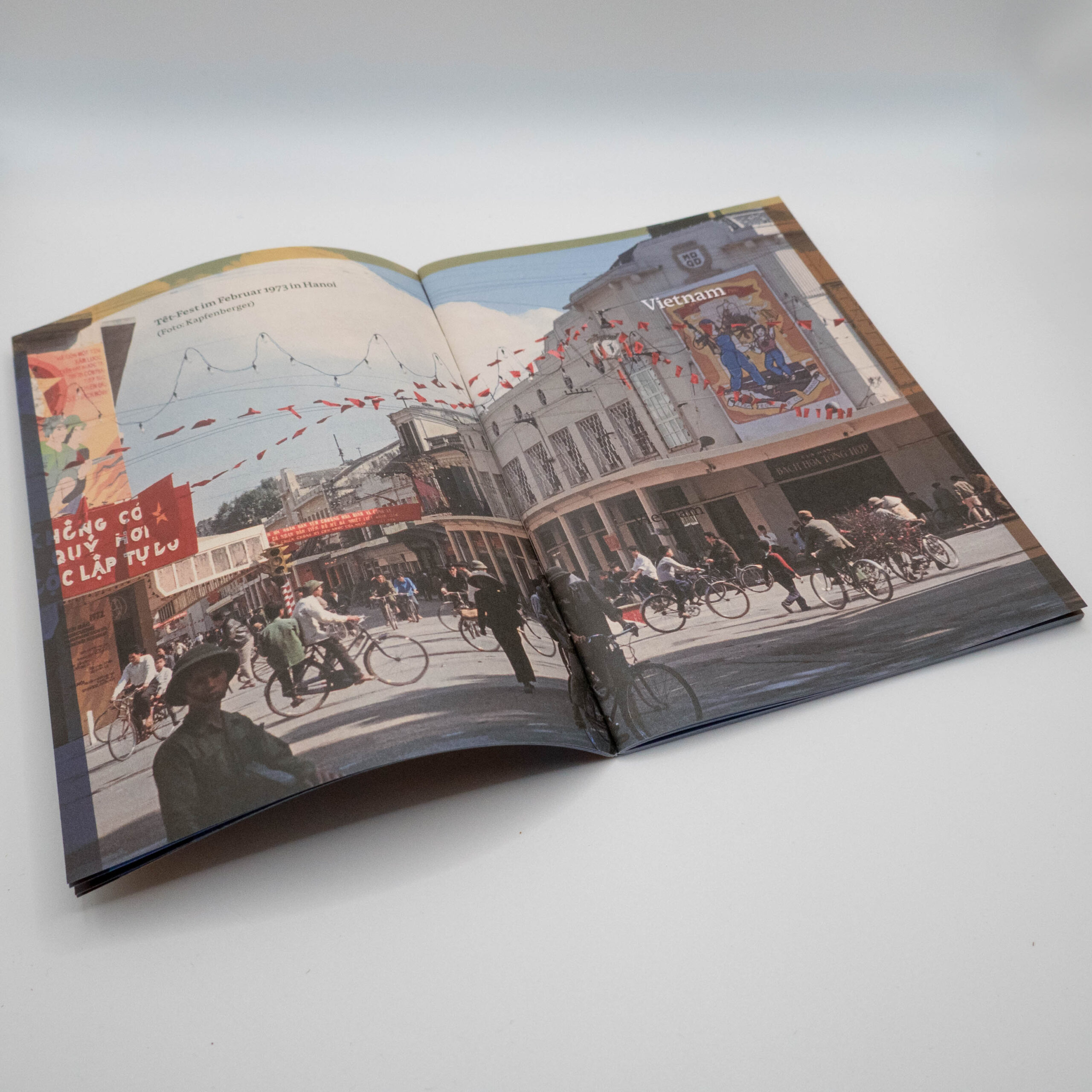 Verlagskatalog 2023, Innenseite Ein doppelseitiges Foto vom Têt-Fest 1973 in Hanoi, mit Fhrrädern, Fuußgängern und Kaufhausfassaden